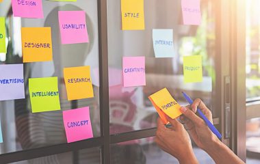 Web designer brainstorming for a strategy plan. Colorful sticky notes with things to do on office board. User experience (UX) concept.